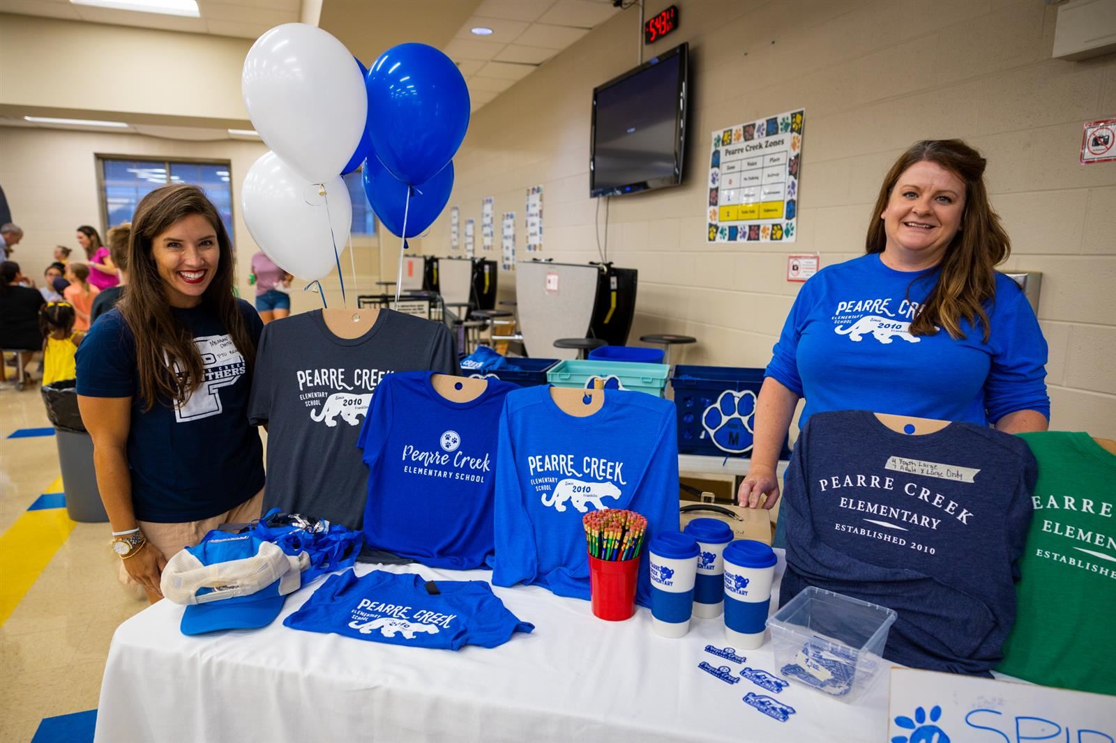 Two PTO volunteers in front of the Spirit Wear table.